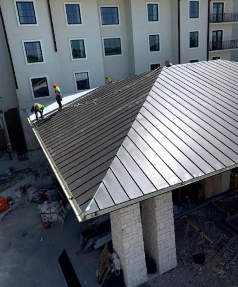 Crew installing standing seam metal roof panels on a commercial project in Mentone